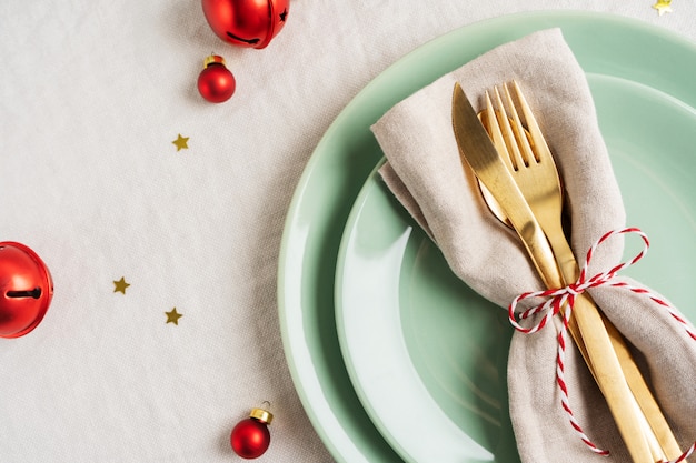 Close view of golden cutlery on light napkin for Christmas table setting.