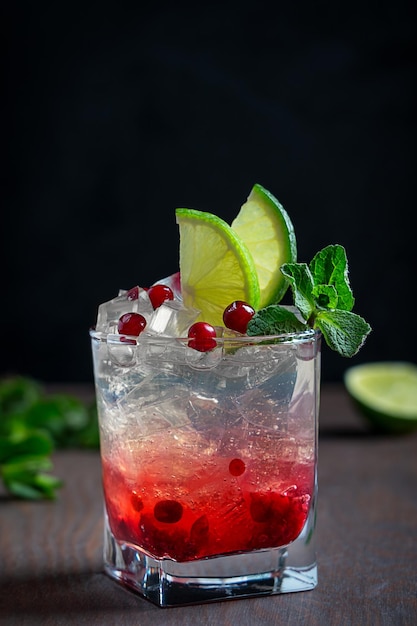 Close view of refreshing lemonade drink made of cranberry in glass with ice cubes lime and mint