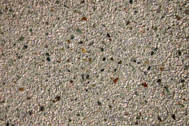 Close view of the textured background of a cement wall mixed with broken glass.