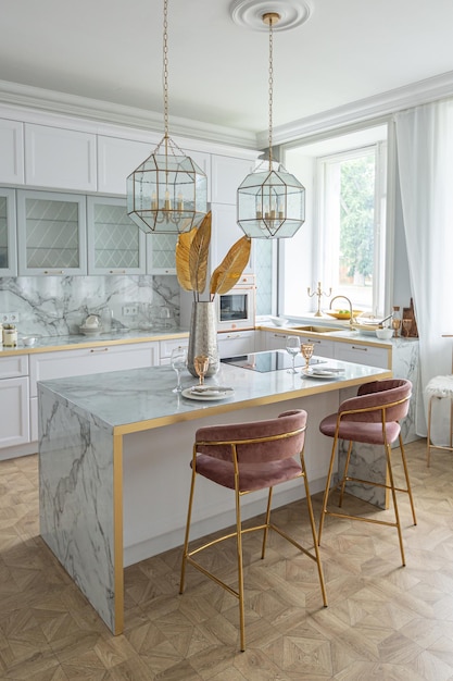 A close view of the white stylish kitchen with a cooking island in the luxurious interior of a modern apartment in light colors with stylish furniture