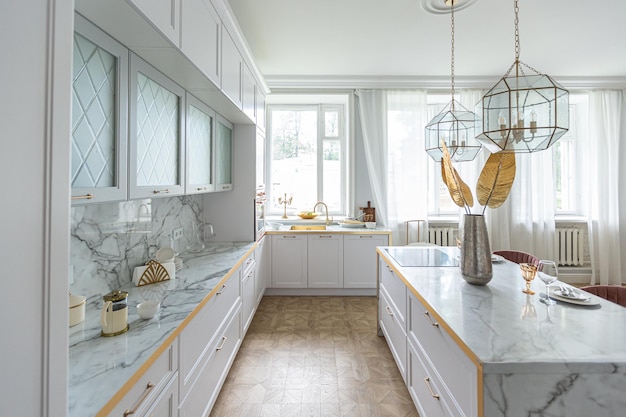 A close view of the white stylish kitchen with a cooking island in the luxurious interior of a modern apartment in light colors with stylish furniture