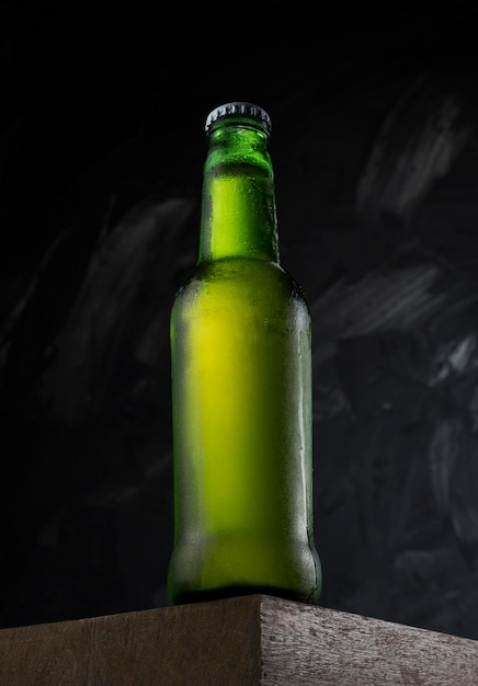 Closed Beer green bottle on a wooden desk Freezing ready to drink