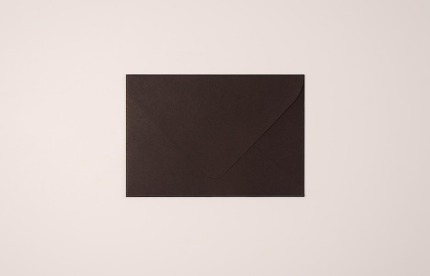 Closed black envelope on a light background of a milky color