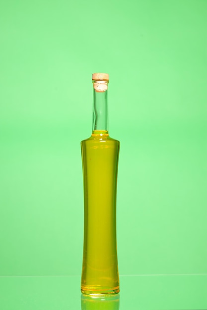 Photo closed bottle of olive oil isolated on green