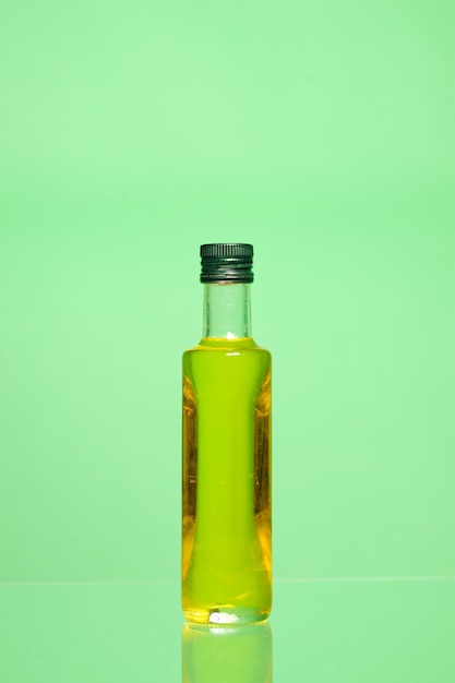 Photo closed bottle of olive oil isolated on green