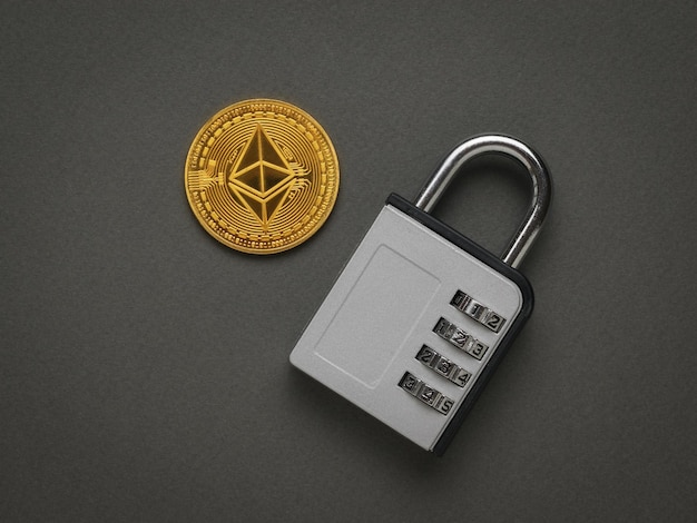 A closed combination lock and a large digital coin on a dark gray background Protection of digital savings Flat lay