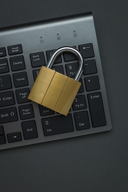 Closed metal lock on a computer keyboard on a dark table. The concept of computer security. Flat lay.