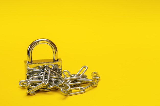 Closed padlock with chain on yellow background with copy space prohibition taboo