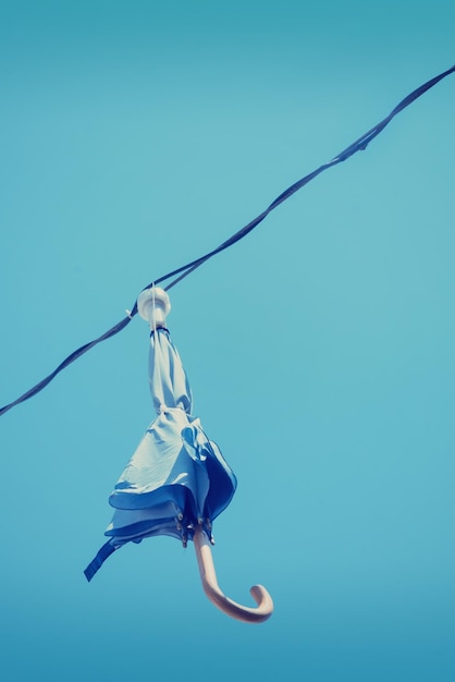 Closed umbrella with lamp hanging on a wire against the blue sky