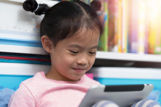 Closed up asian thai girl child kid sit book self funny to reading tablet