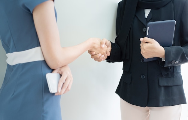 Closed up hand cheacking of two woman one in muslim hijab hand hold tablet one dress in modern suit hand hold smart phone,success business concept.