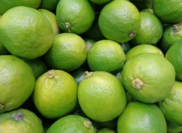 Closed up Pile of Vibrant Green Ripe Limes with Stem, for Background