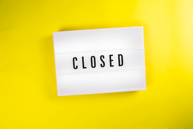 Closed word on lightbox vintage billboard on yellow background isolated