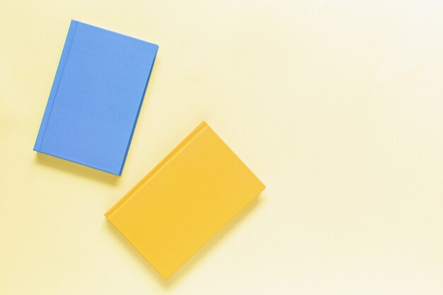 Closed yellow and blue notebooks isolated on beige