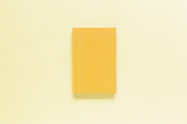 Closed yellow notebook isolated on beige