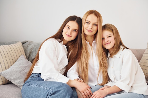 Closeness of the people Young mother with her two daughters at home at daytime