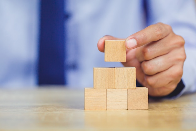 Closer up hands of businessmen,stacking wooden blocks into steps.