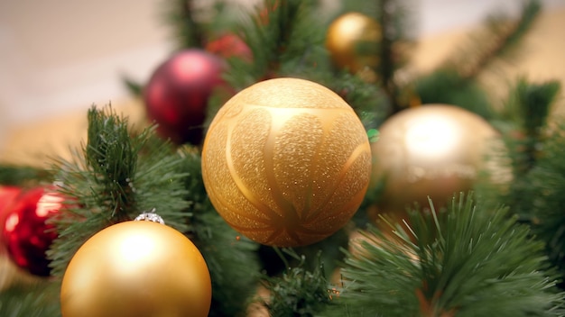 Closeup 4k footage of beautiful golden bubable hanging and rotating on Christmas tree branch at living room