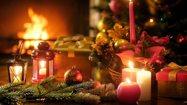 Closeup 4k footage of burning fireplace in living room and beautiful table decorated with candles, baubles and Christmas gifts and presents. Perfect shot for winter celebrations and holidays