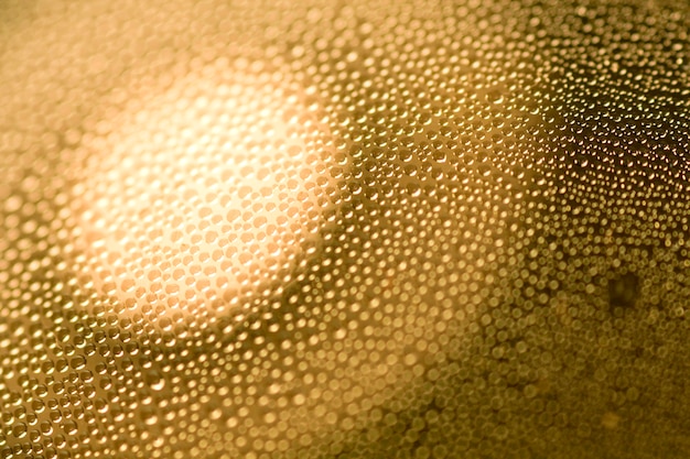 Closeup abstract of many condensated drops of water with a focus of light circle.