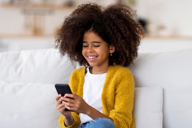 Closeup of african american little girl using smartphone at home