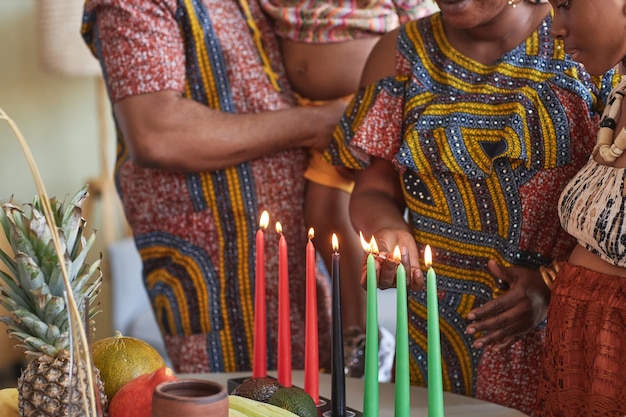 Closeup of african family in national costumes lighting candles to celebrate kwanzaa holiday