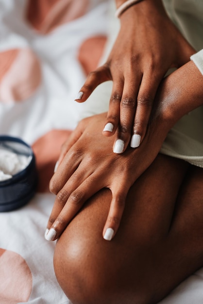 Closeup of an African female applying hand cream in the bedroom