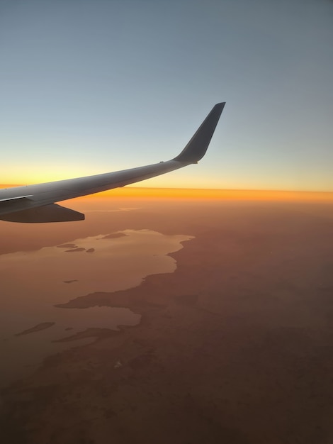 Closeup of airplane wing above ground at sunset background. Travel long flights concept