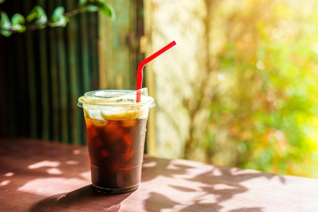 Closeup of Americano ice coffee or black coffee in cup mug on glass wood desk office desk in coffee shop at the cafe in gardenduring business work concept