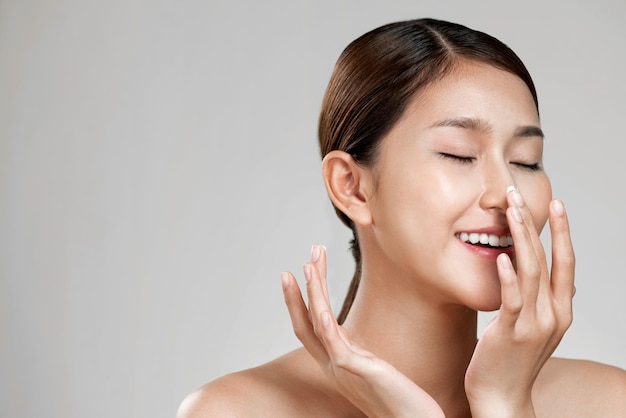 Closeup ardent girl with soft makeup applying moisturizing cream on her nose