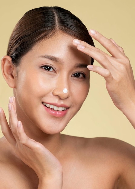 Closeup ardent girl with soft makeup applying moisturizing cream on her nose