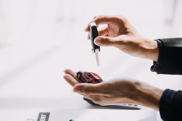 Closeup of Asian female signing car insurance document or lease paper contract or agreement Buying or selling new or used vehicle with car keys on table