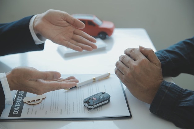 Closeup asian male people car salesman or sales manager offers to sell a car and explains and reads the terms of signing a car contract and insurance