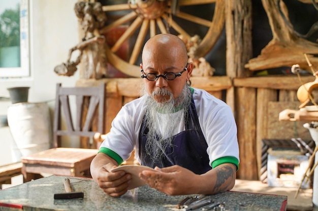 Closeup Asian man leather product maker looking at pieces leather skins to make products in his shop