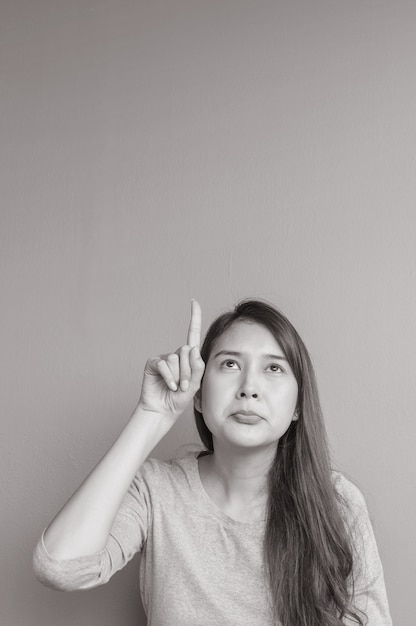 Closeup asian woman holds up one finger point to space with boring face