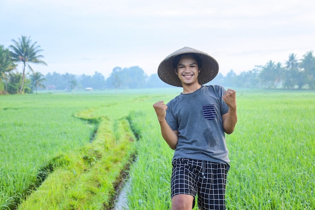 Closeup of attractive cheerful young Asian farmer rejoicing having success attainment to growing pa