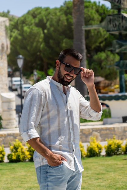 Closeup of an attractive young male tourist smiling and holding his glasses in Cesme Turkey