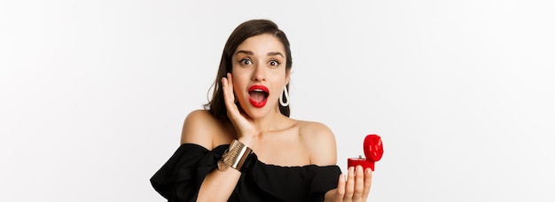 Closeup of attractive young woman with red lipstick makeup on looking amazed after receiving marriag