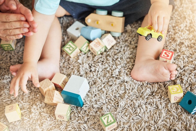 Closeup of baby learning with toys block puzzle and train to help hand eye coordination on floor in home Young child learn with education games on carpet for cognitive development and fun in house