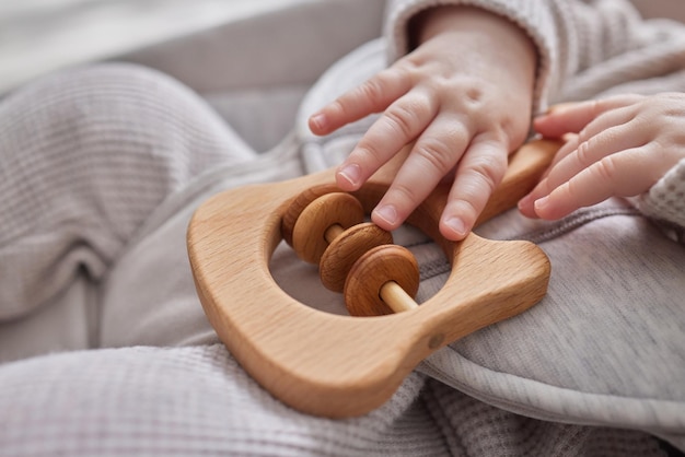 Photo closeup of a baby s hand playing with a wooden toy unfocused background