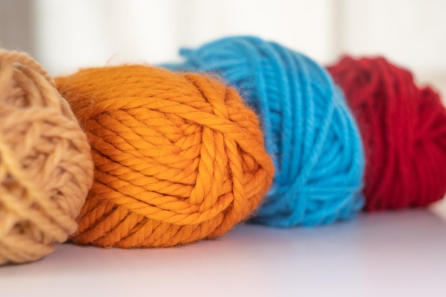 Closeup on balls of colored wool yarn on white background. Copy space