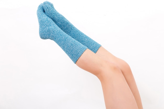 Closeup of the bare legs of a young woman wearing blue socks with his feet.