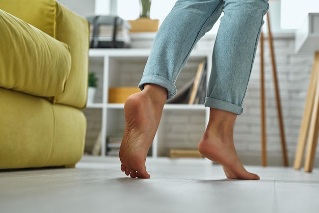 Closeup of barefoot woman walking on wooden floor at home