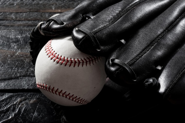 Closeup baseball glove and baseball on wood board dark theme sport concept