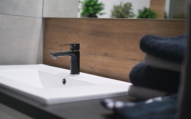 Closeup bathroom interior washbasin with mirror black faucet and dark towels