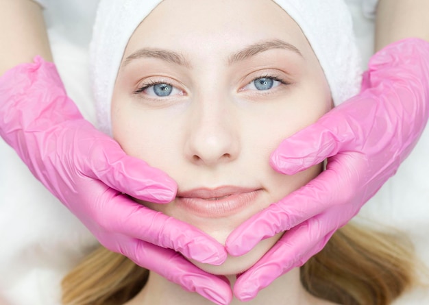 Photo a closeup beautician does rejuvenating facial treatments for female clients at a spa or salon a cosmetologist gives a patient a facelift massage in the clinic of aesthetic medicine beauty cosmetology