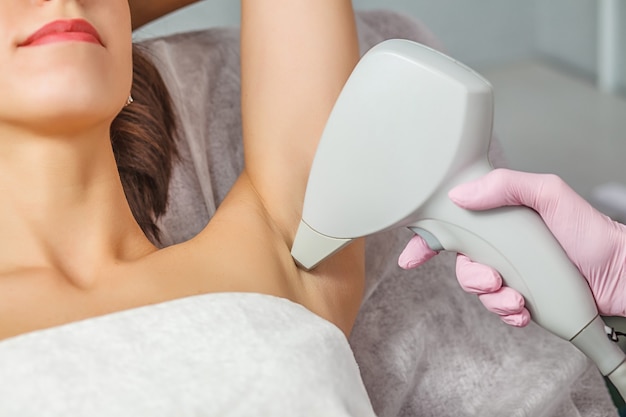 Closeup of beautician removing hair of woman's armpit