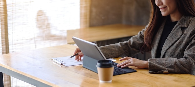 Closeup  of a beautiful asian businesswoman working and using digital tablet as a computer pc with financial document on the table