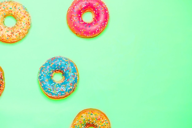 Closeup of beautiful multicolored sweet donuts on mint background with copy space. Food, restaurant, bakery concept