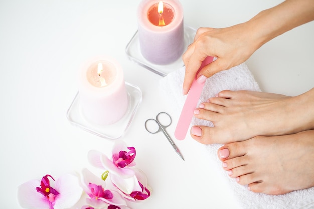 Closeup of beautiful woman legs getting pedicure at home.